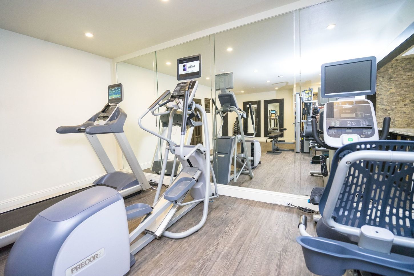 A gym with treadmills , ellipticals , and a large mirror.