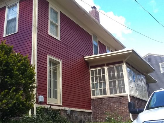 A red house with a white car parked in front of it