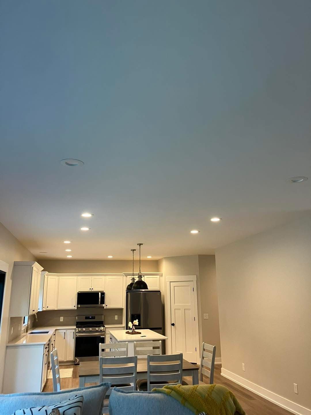 Kitchen with white cabinets, island, appliances, and dining table; neutral walls and ceiling.