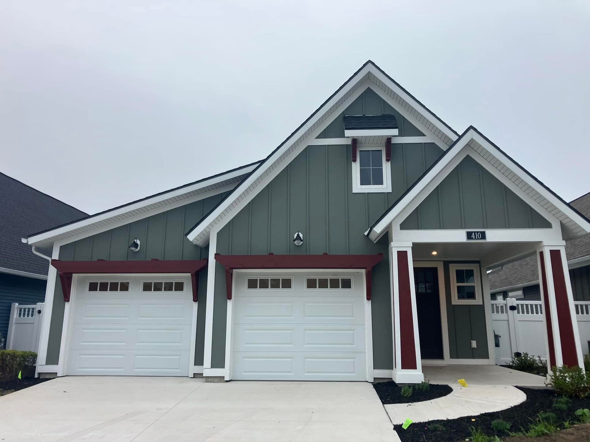 Green and white craftsman-style house with a two-car garage and a small front porch.