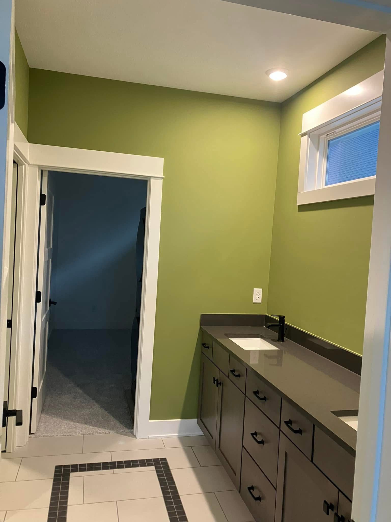 Bathroom with olive green wall, gray vanity, and a window.