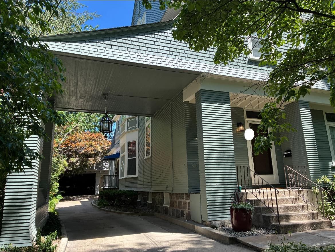 A house with a driveway leading to it and trees in front of it.