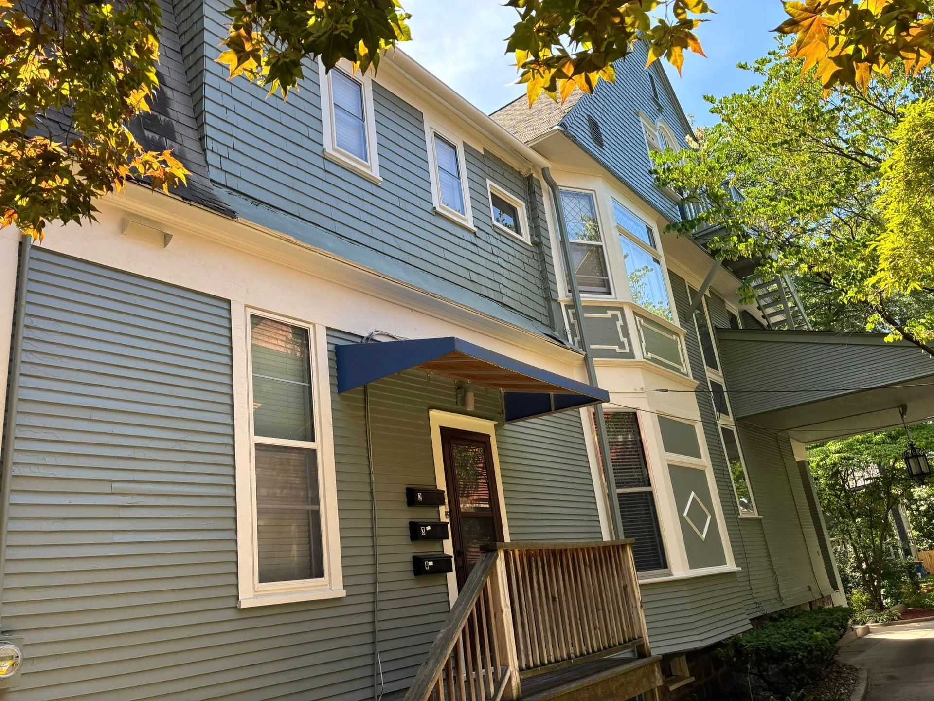 A blue and white house with a blue awning over the front door.