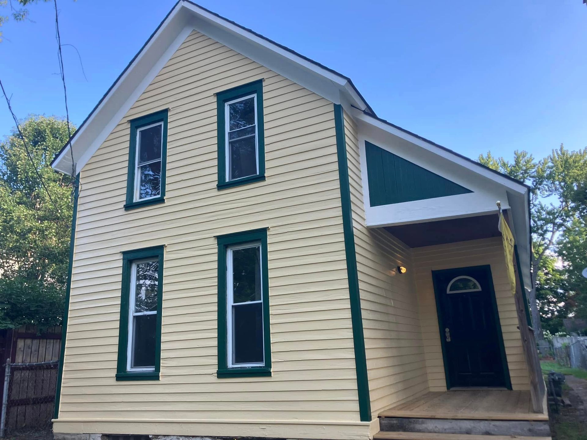 A yellow house with green trim and a black door