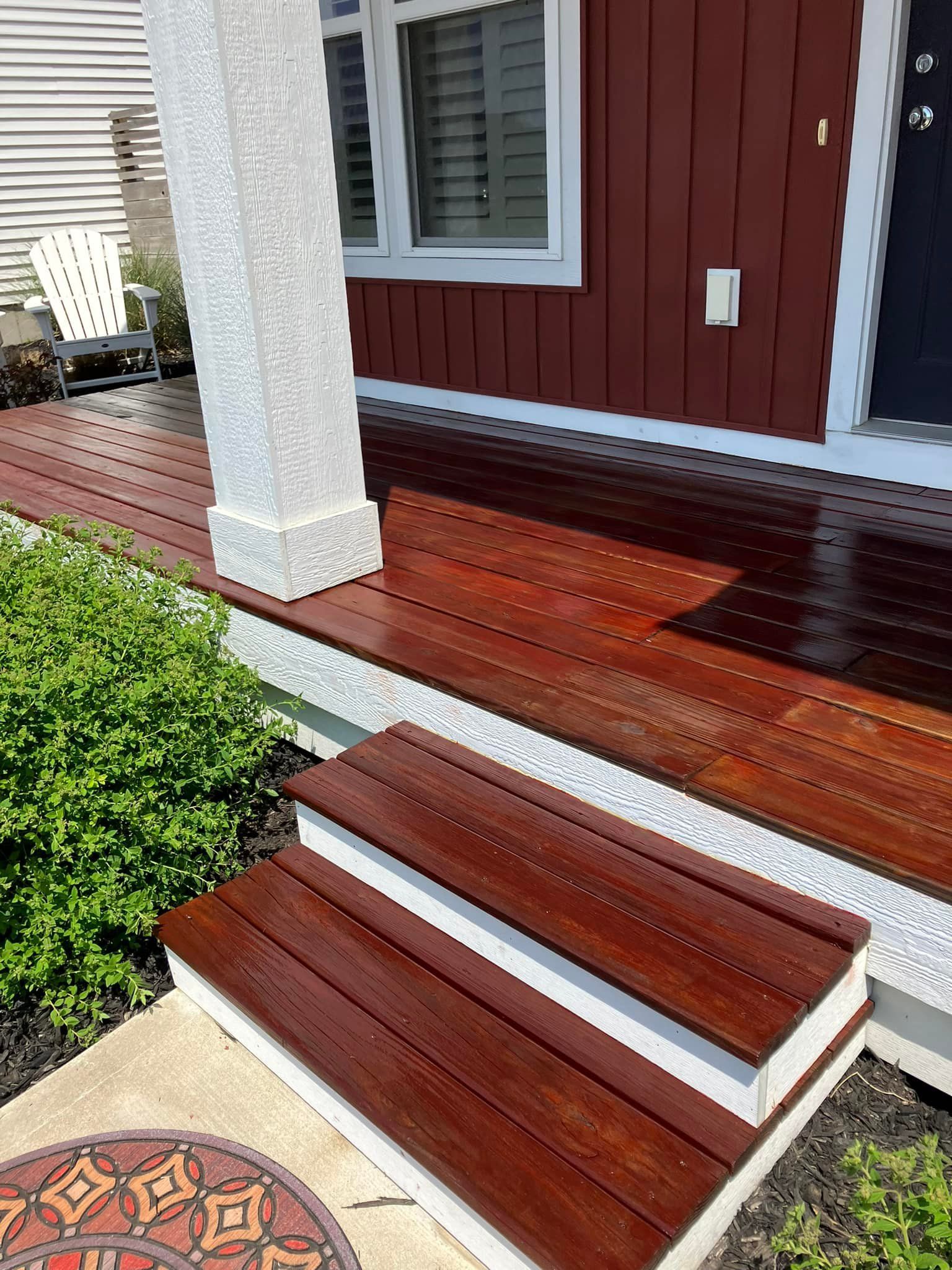 A wooden deck with stairs leading up to a red house.