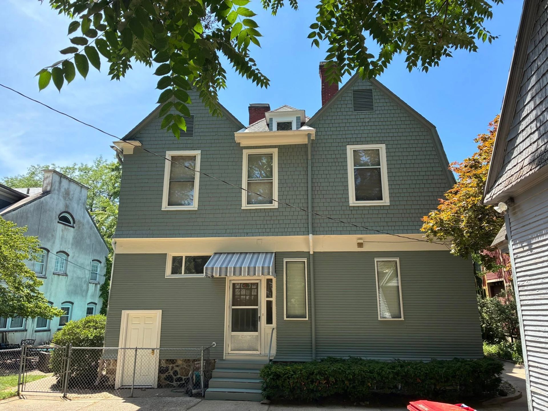 A large grey house with a white door and awning