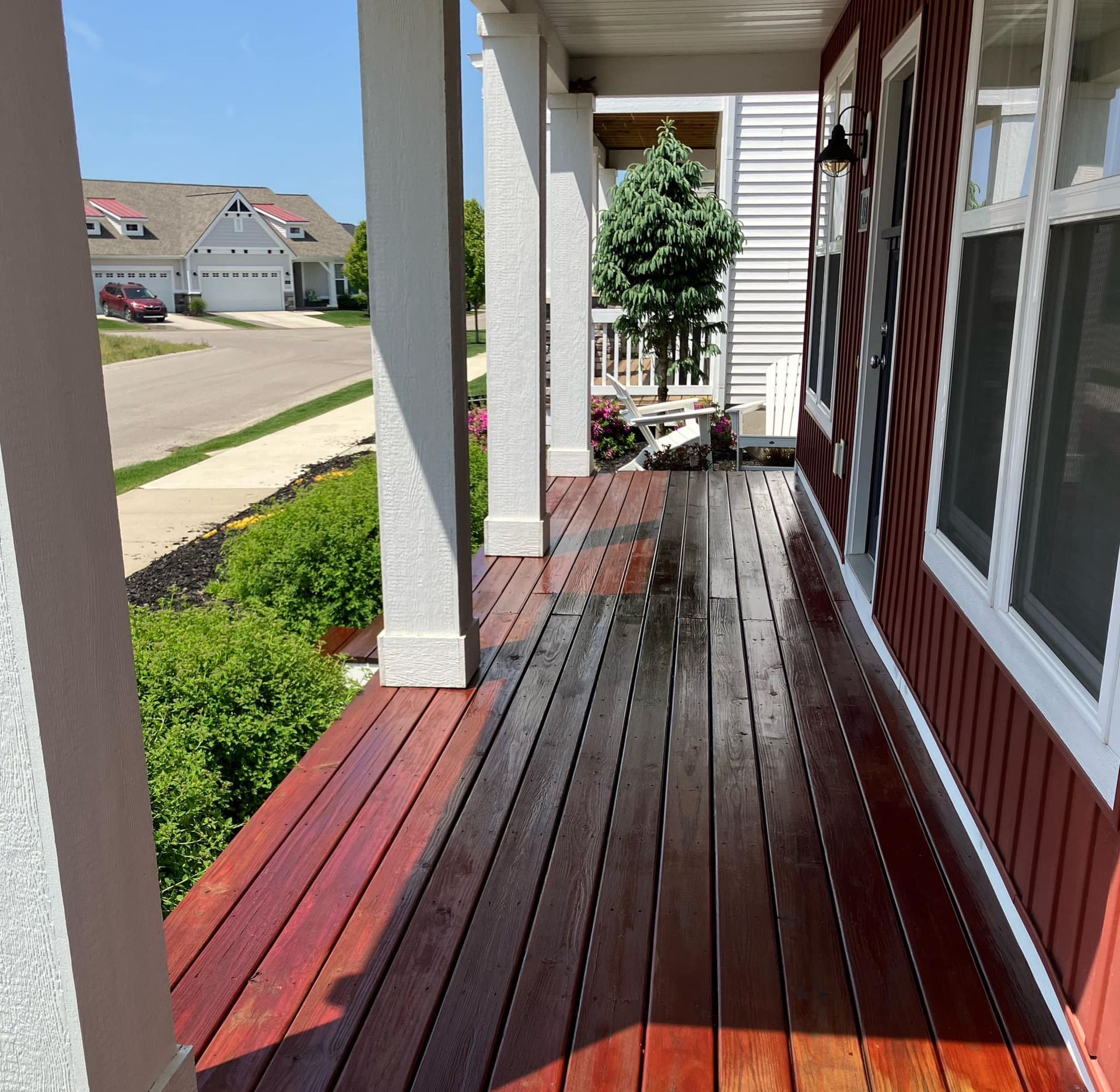 A wooden porch with a white house in the background