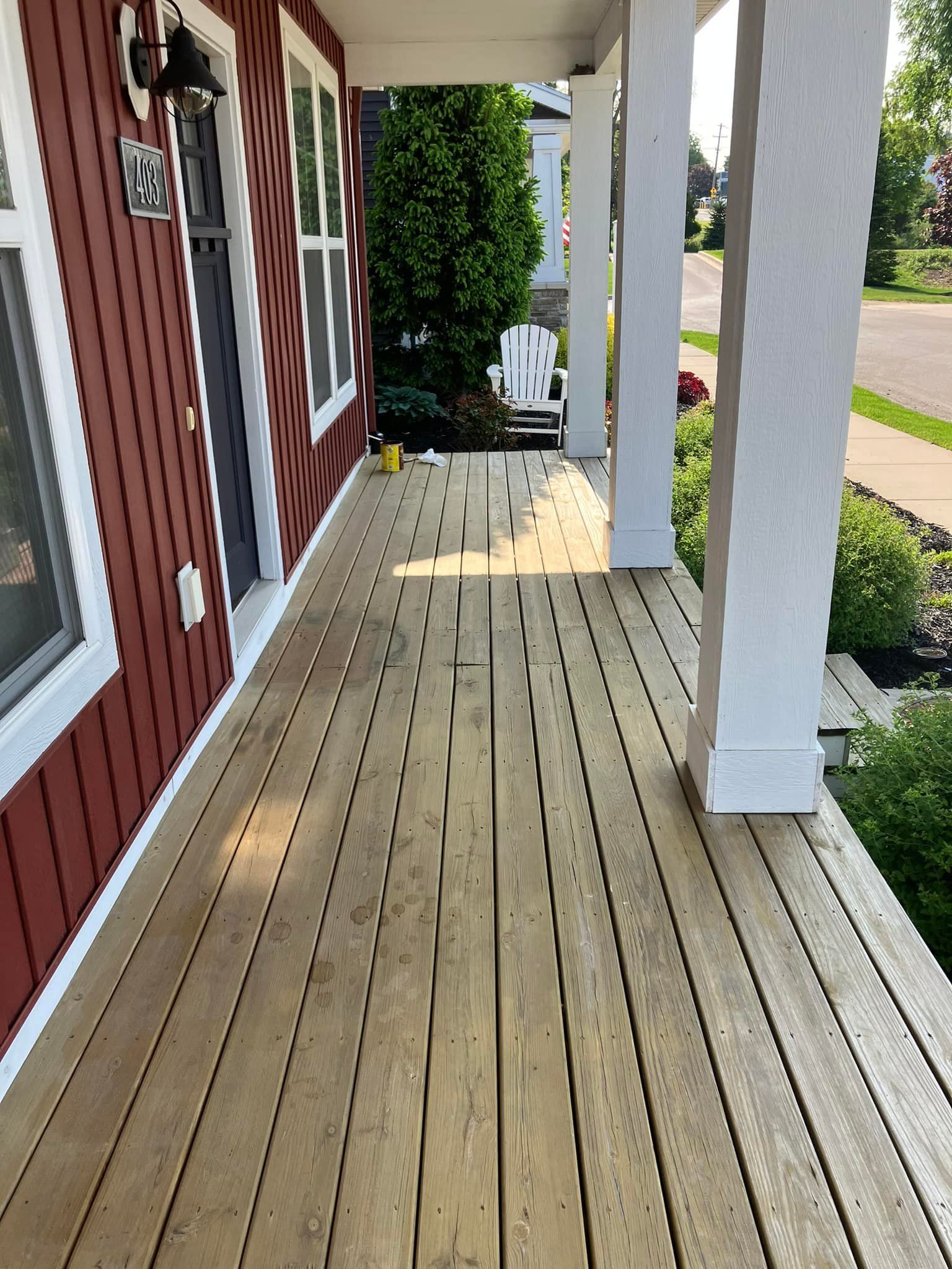 A wooden porch with a red house in the background
