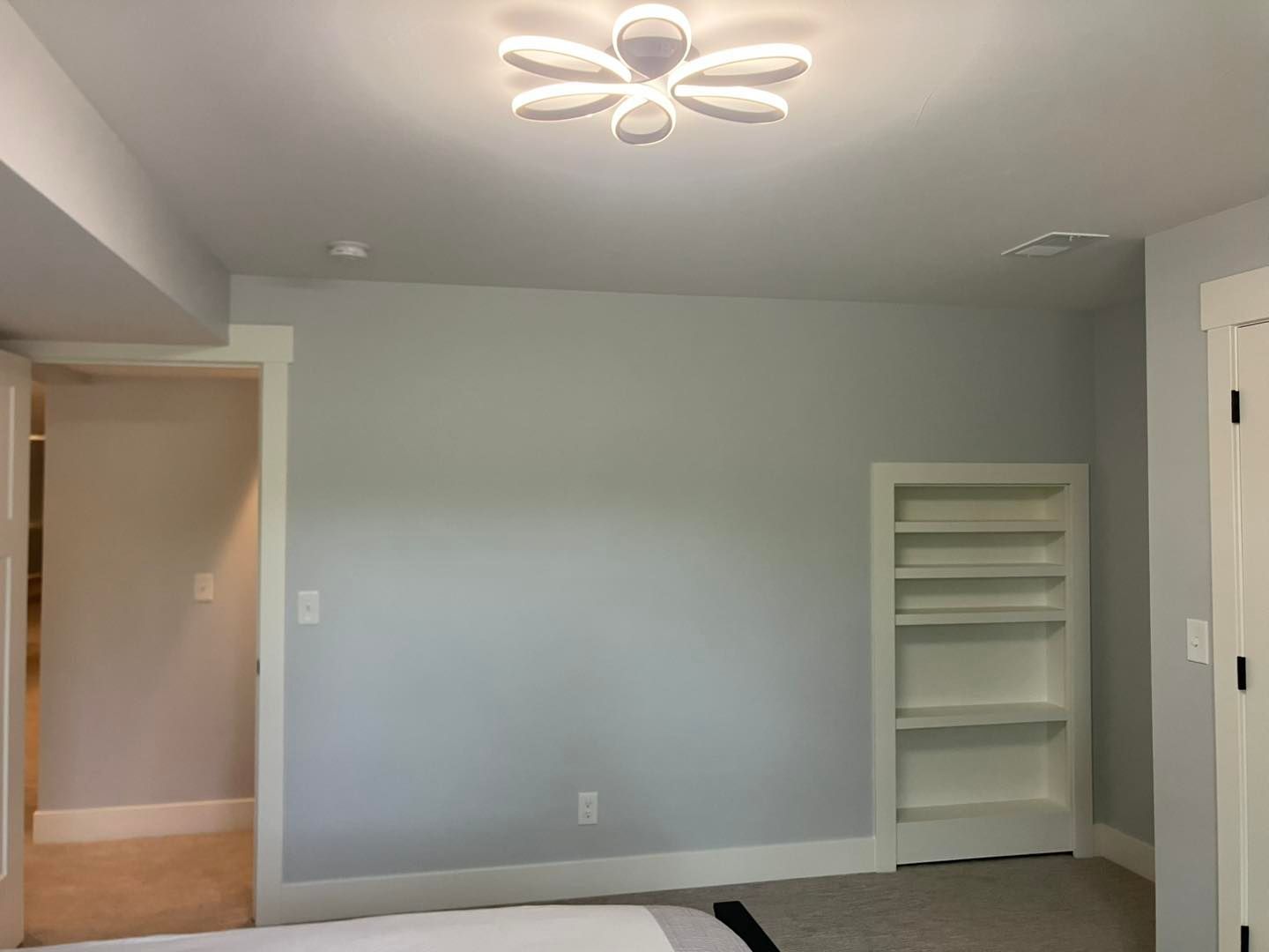 A bedroom with a ceiling light and a bookshelf