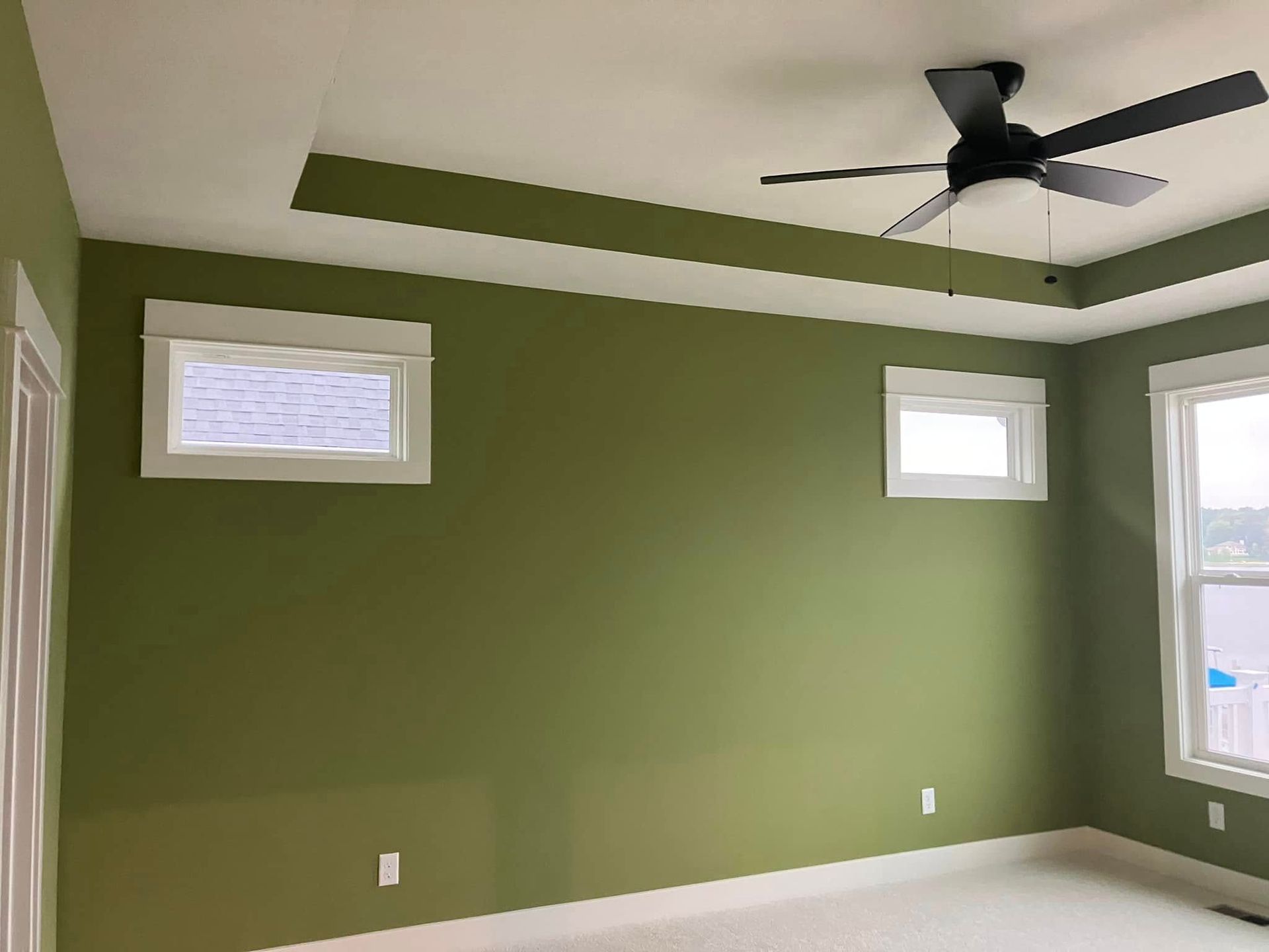 A room with green walls and a ceiling fan.