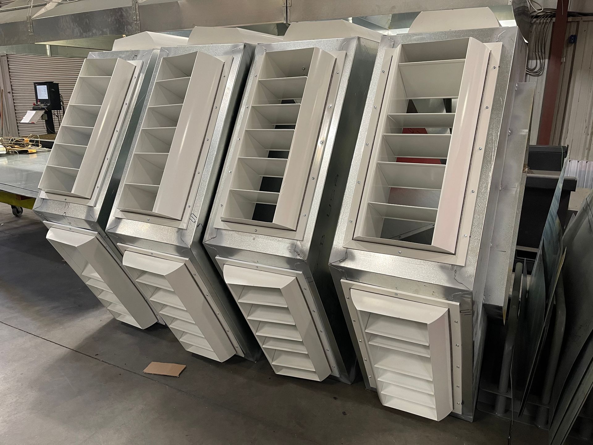 A row of white shutters are stacked on top of each other in a warehouse.