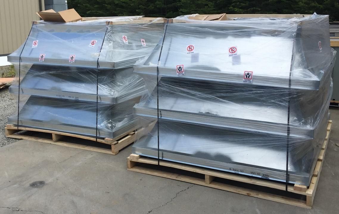 A bunch of metal pieces wrapped in plastic are sitting on wooden pallets.