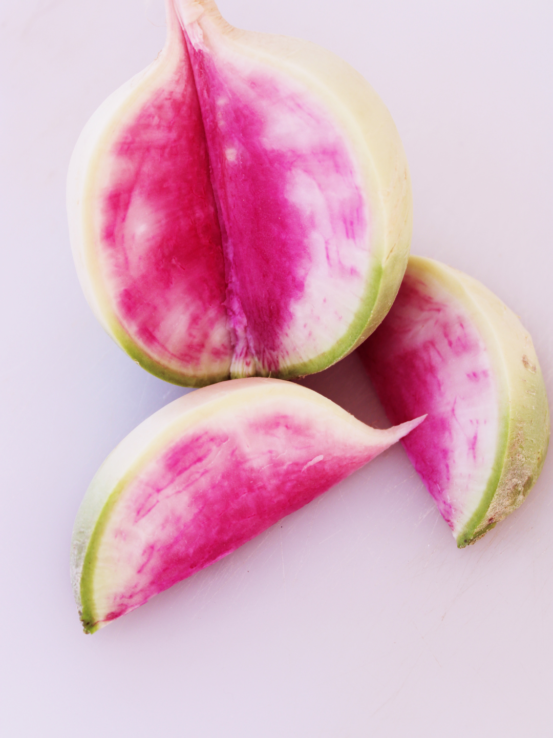 Watermelon radish, sliced open to reveal bright pink interior and white rind.