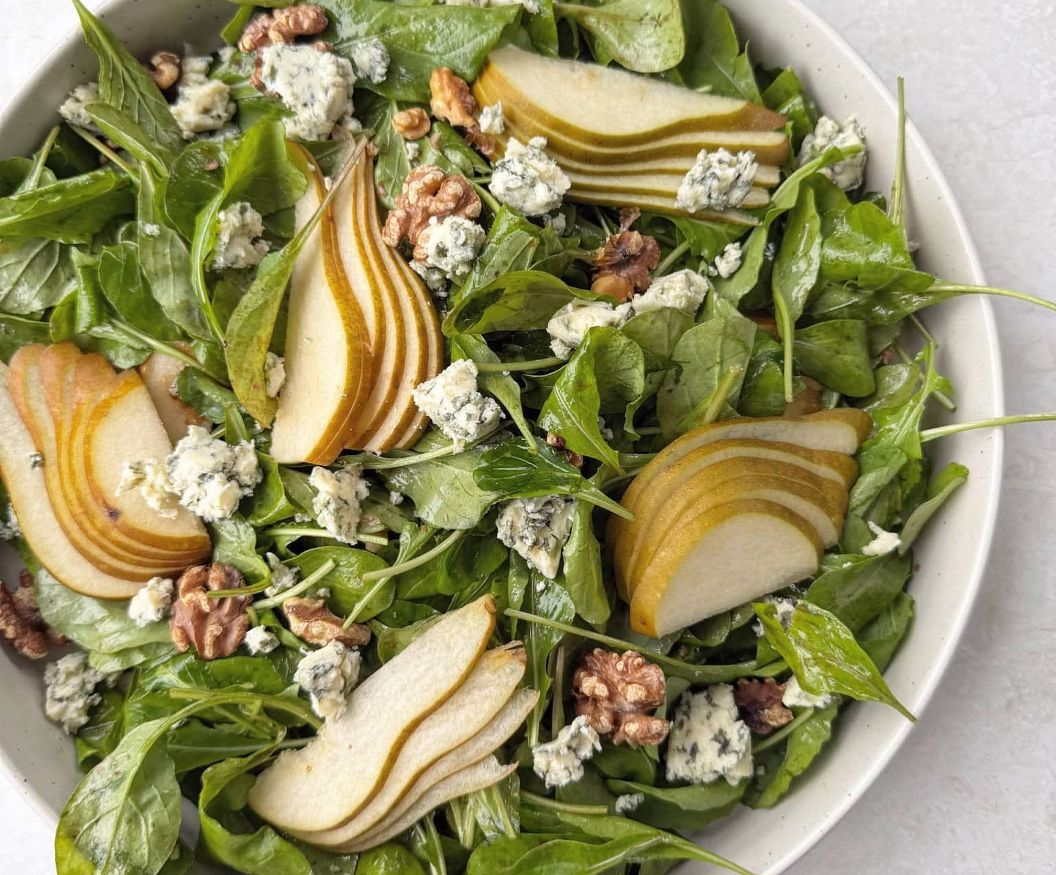 Arugula salad with sliced pears, blue cheese, and walnuts.