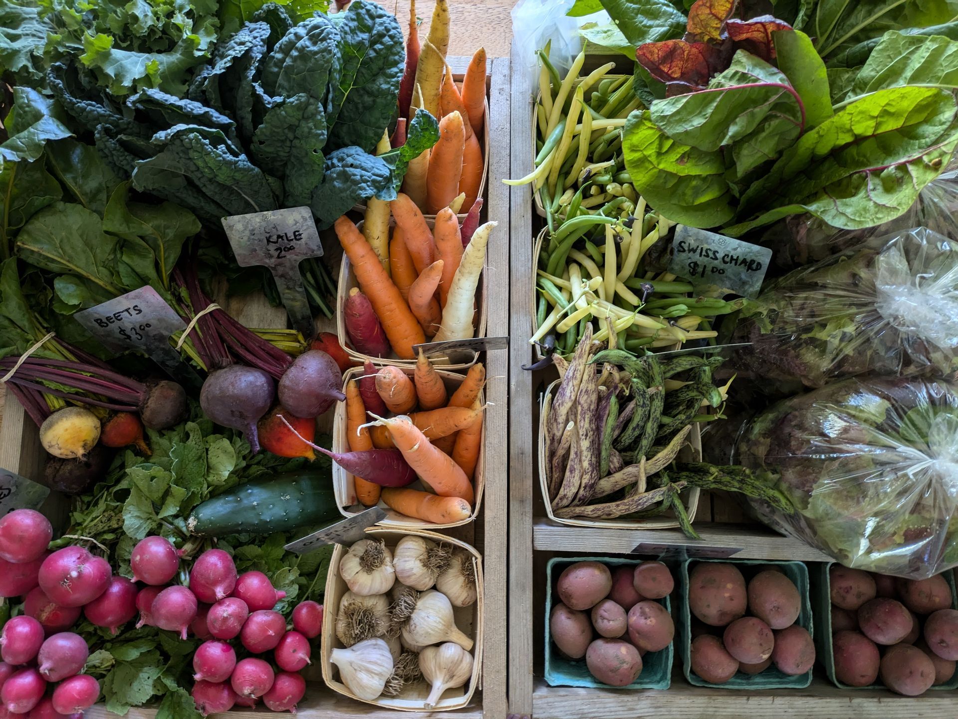 Wooden crates overflowing with colorful fresh vegetables at a market.