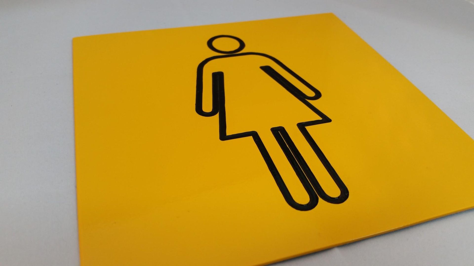 A Yellow Sign With a Black Outline of a Woman on It — Total Engraving In Sandgate, NSW