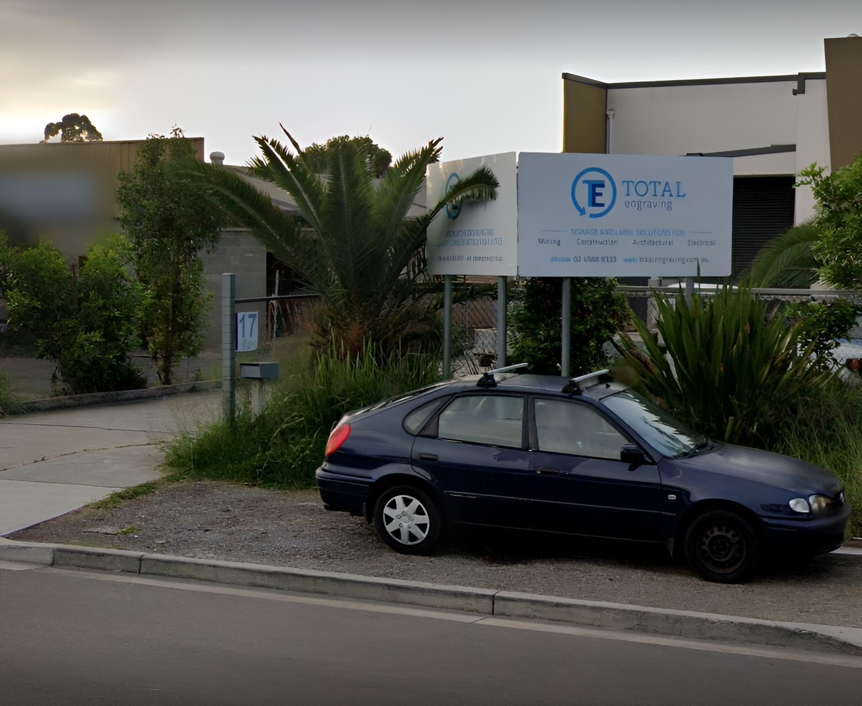 A Blue Car is Parked in Front of a Total Sign — Total Engraving In Sandgate, NSW