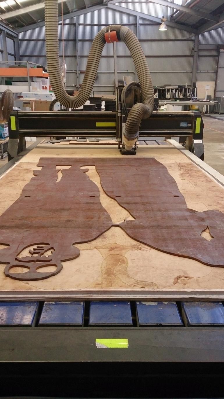 A Machine is Cutting a Piece of Wood in a Warehouse — Total Engraving In Sandgate, NSW