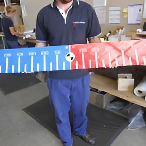 A Man is Holding a Red and Blue Ruler With Numbers on It — Total Engraving In Sandgate, NSW