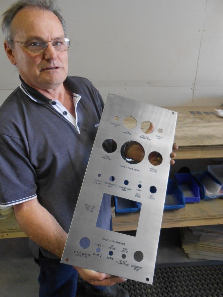 A Man is Holding a Piece of Metal in His Hands — Total Engraving In Sandgate, NSW