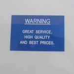 A Blue Sign That Says Warning Great Service High Quality and Best Prices — Total Engraving In Sandgate, NSW