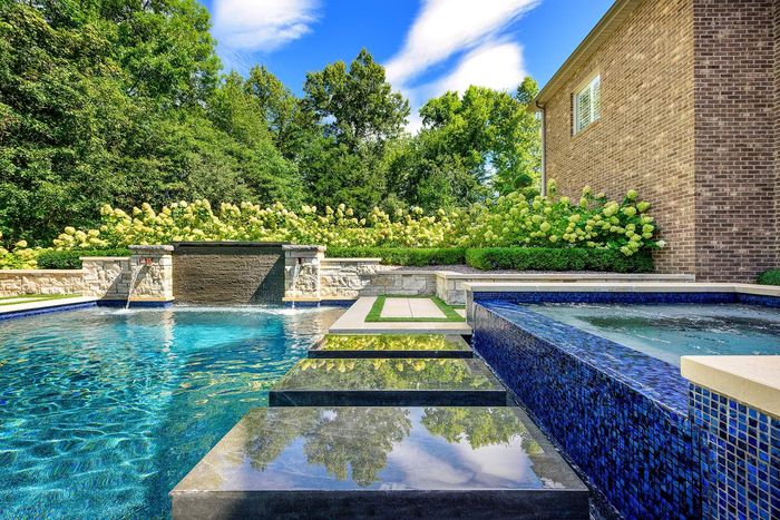 There is a large swimming pool in the backyard of a house.