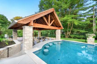 A large swimming pool with a wooden gazebo over it.