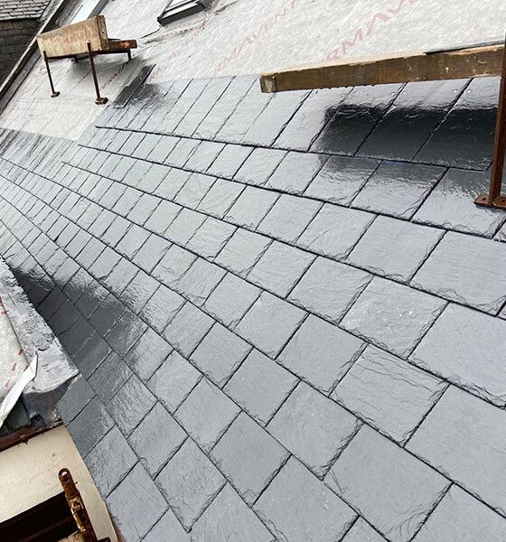 Newly installed gray slate roof with wooden scaffolding.