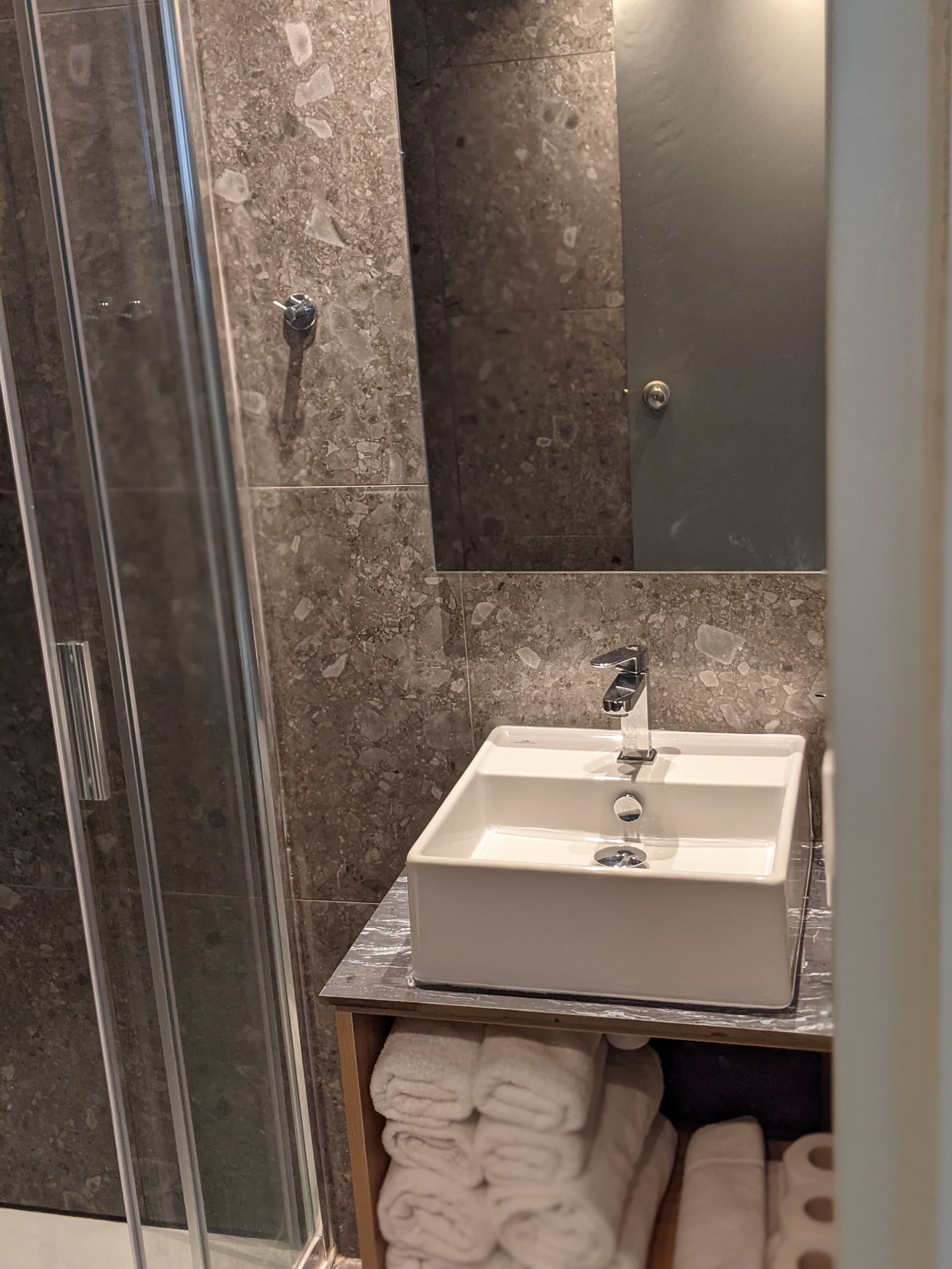 A bathroom with a sink , mirror and shower.