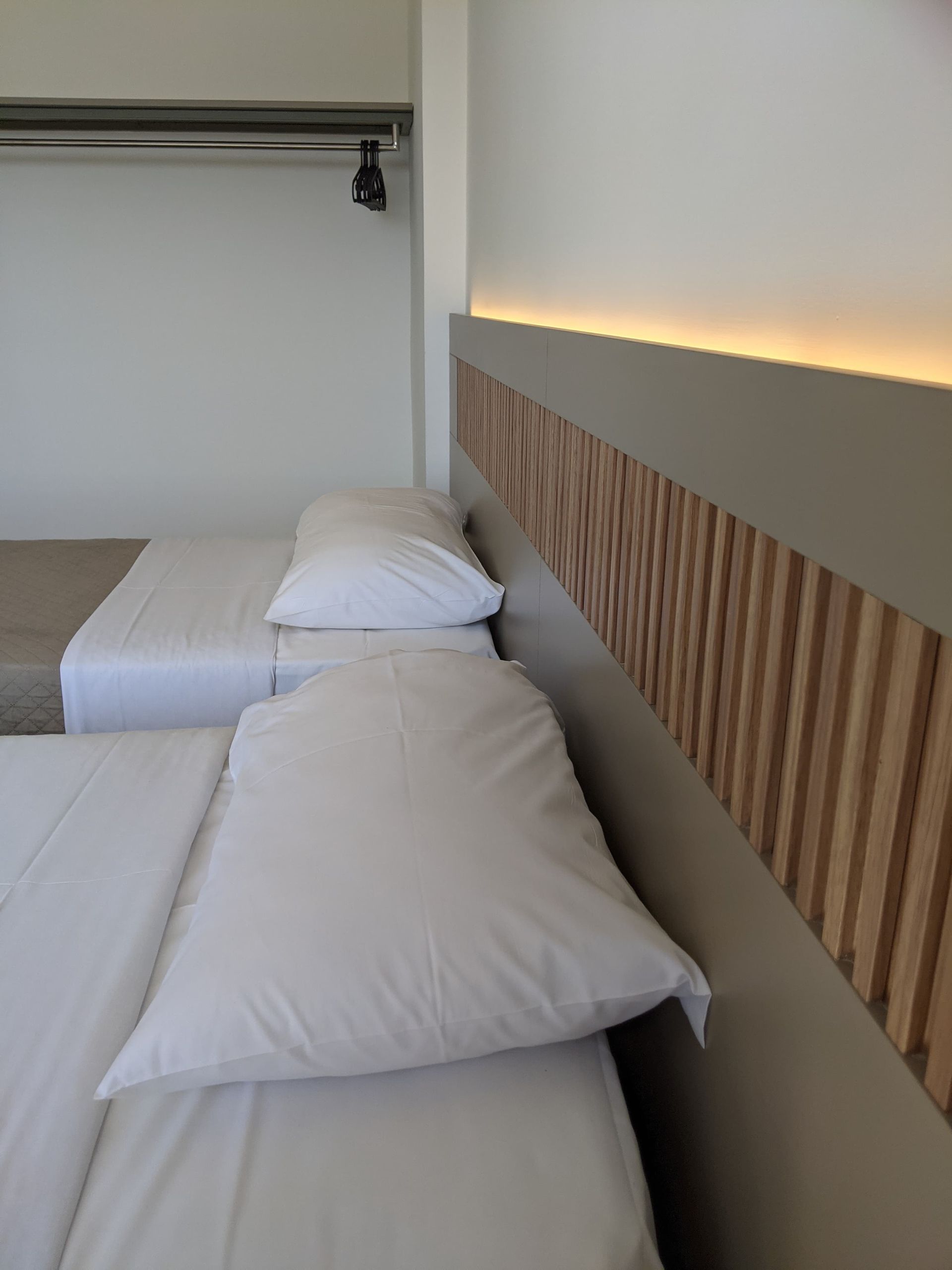 A hotel room with two beds and a wooden headboard
