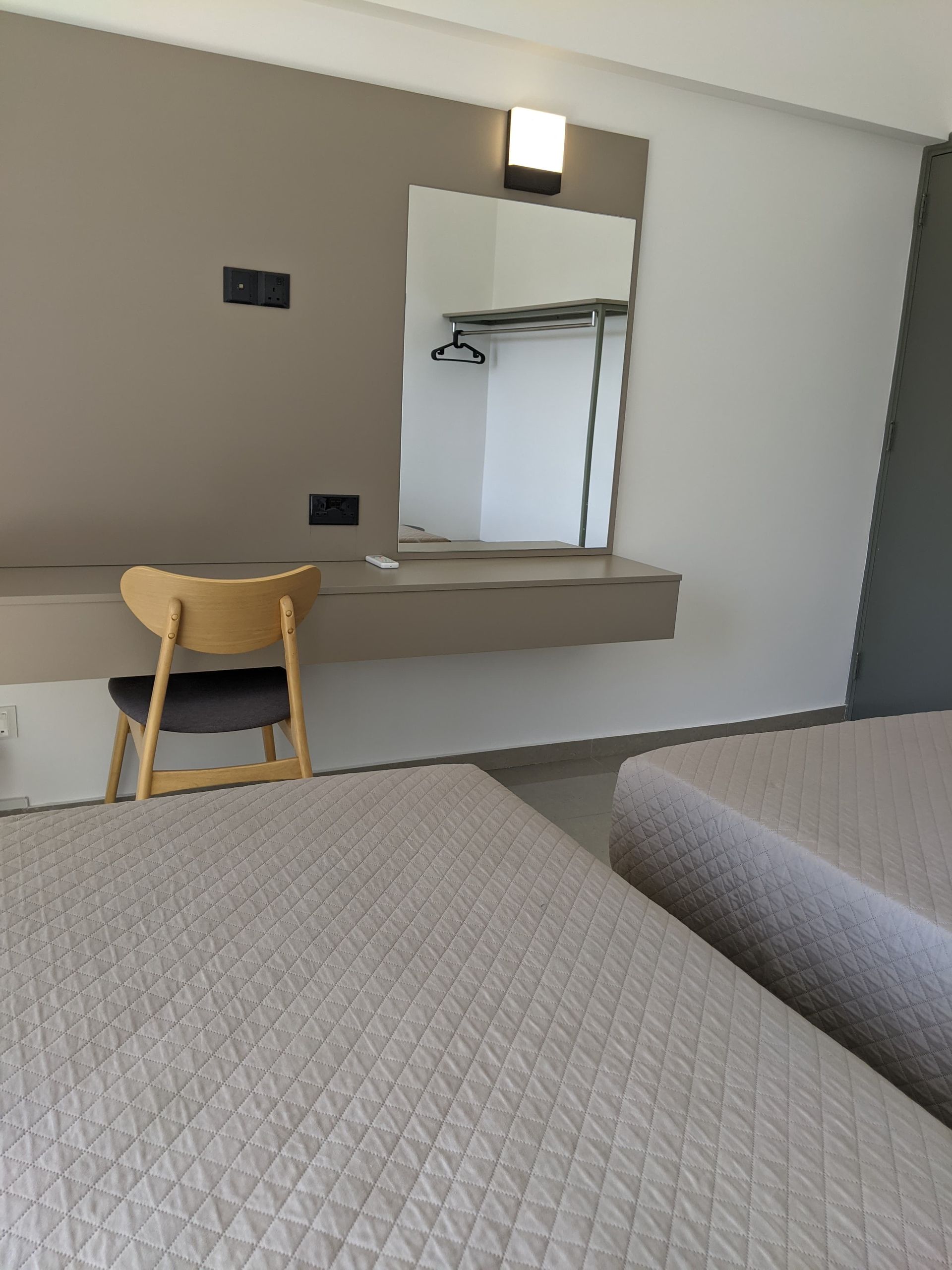 A hotel room with two beds a desk and a mirror