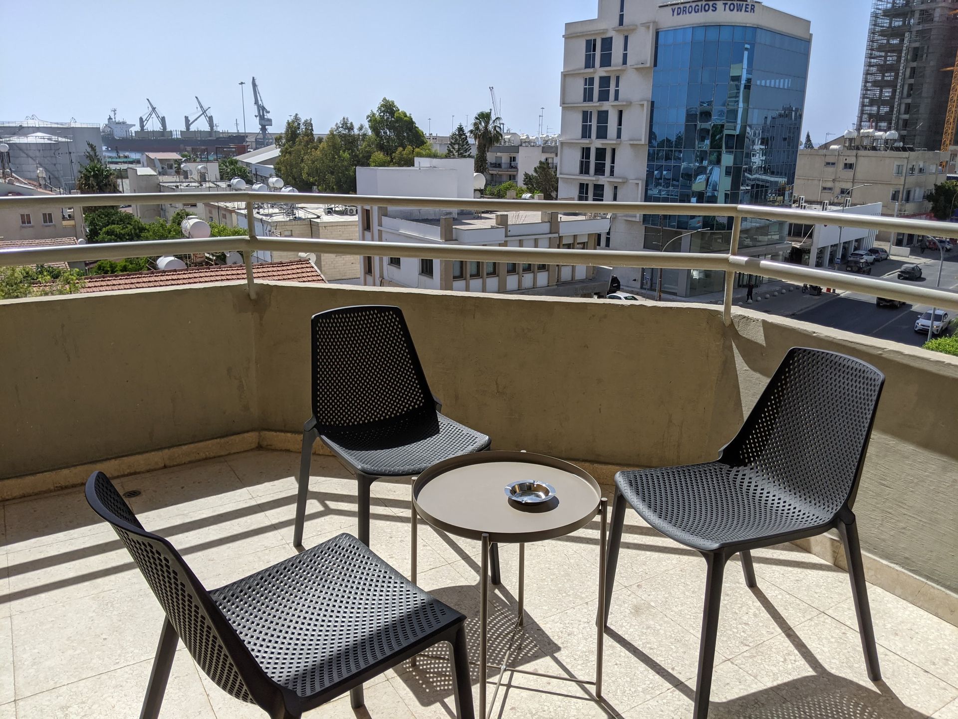 Two chairs and a table on a balcony overlooking a city