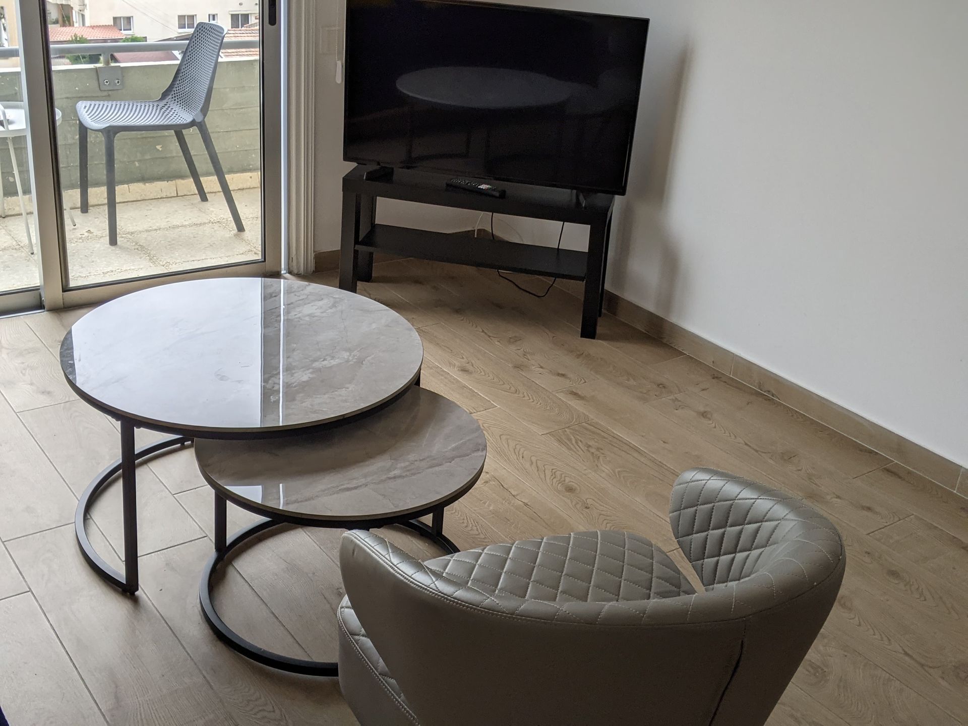 A living room with three tables and a flat screen tv