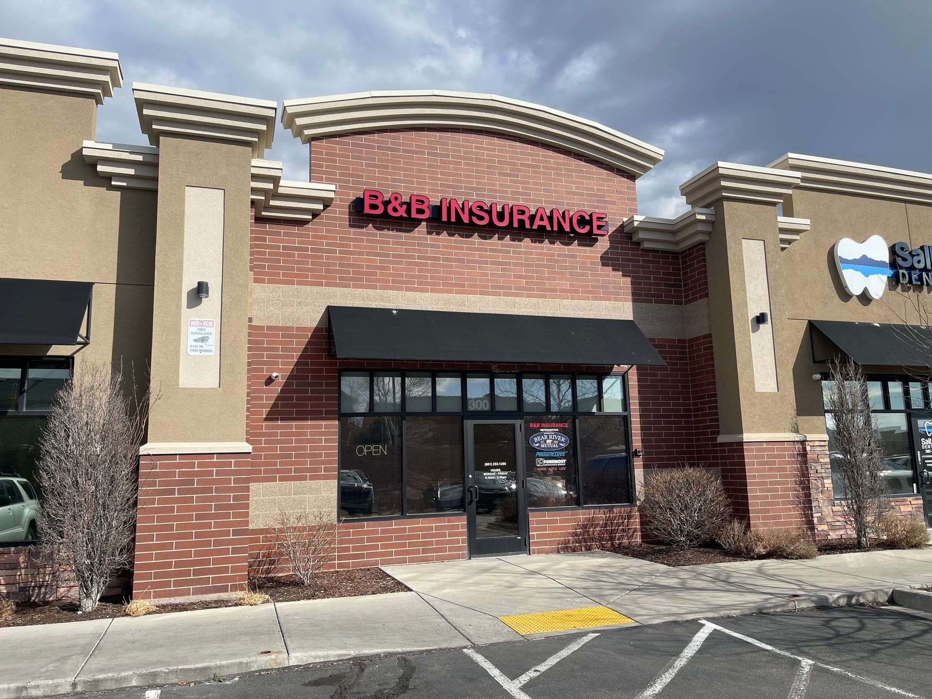 Group of professionals in suits and hard hats discuss plans in front of a modern glass building.