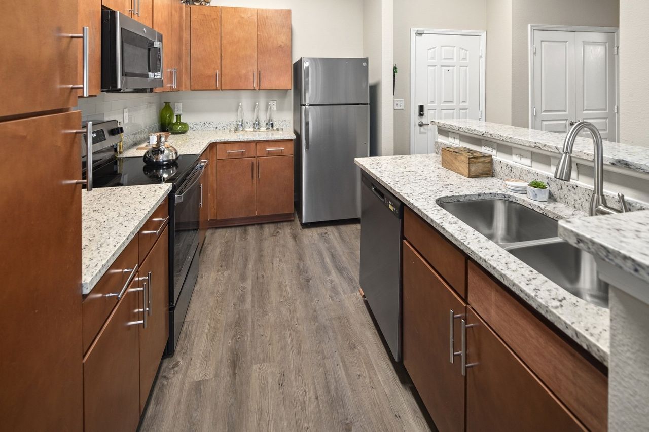 A kitchen with stainless steel appliances , granite counter tops , and wooden cabinets.