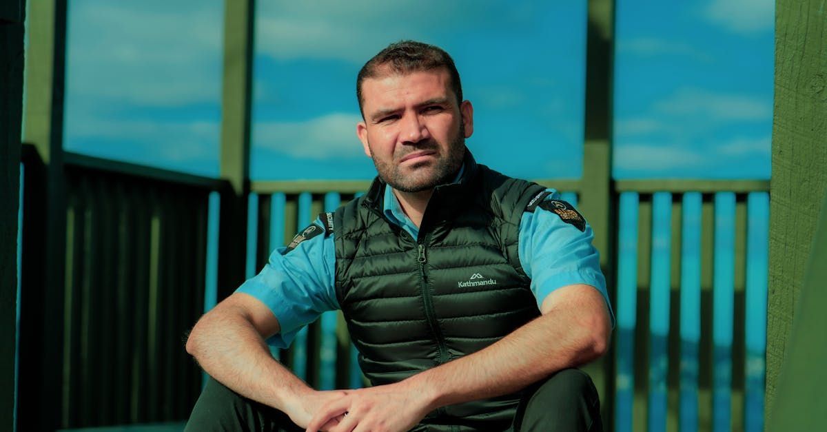 A man is sitting on a balcony with his hands folded.