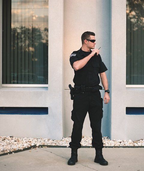 A man in a black uniform is standing in front of a building