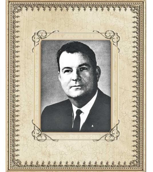 Framed black-and-white portrait photo of a man in a suit and tie on a decorative beige mat