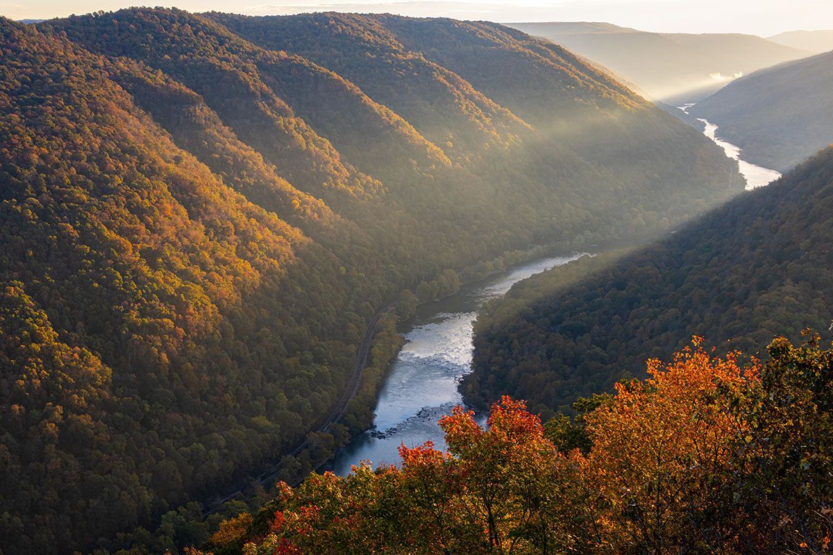 Sunlit river winding through autumn-covered mountains