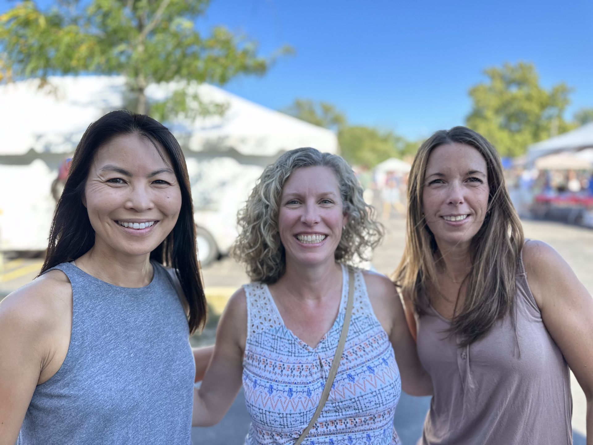 Three women are posing for a picture together at a festival.