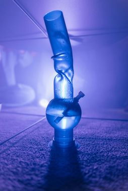 A blue bong is sitting on a purple surface.