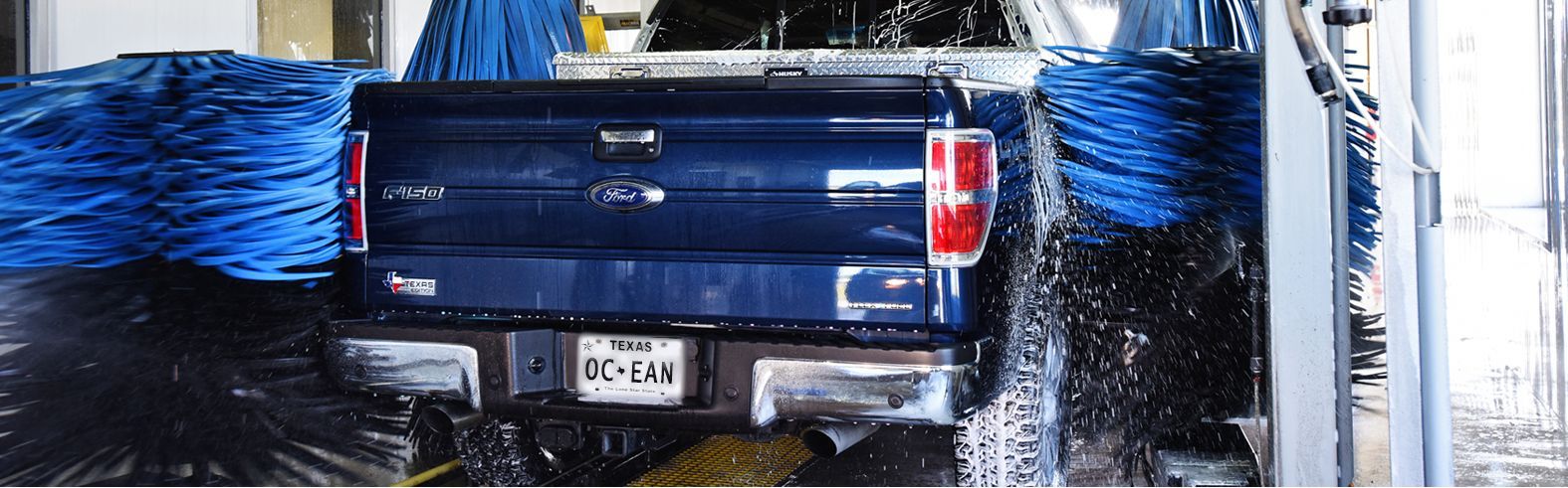 A blue truck is being washed in a car wash.