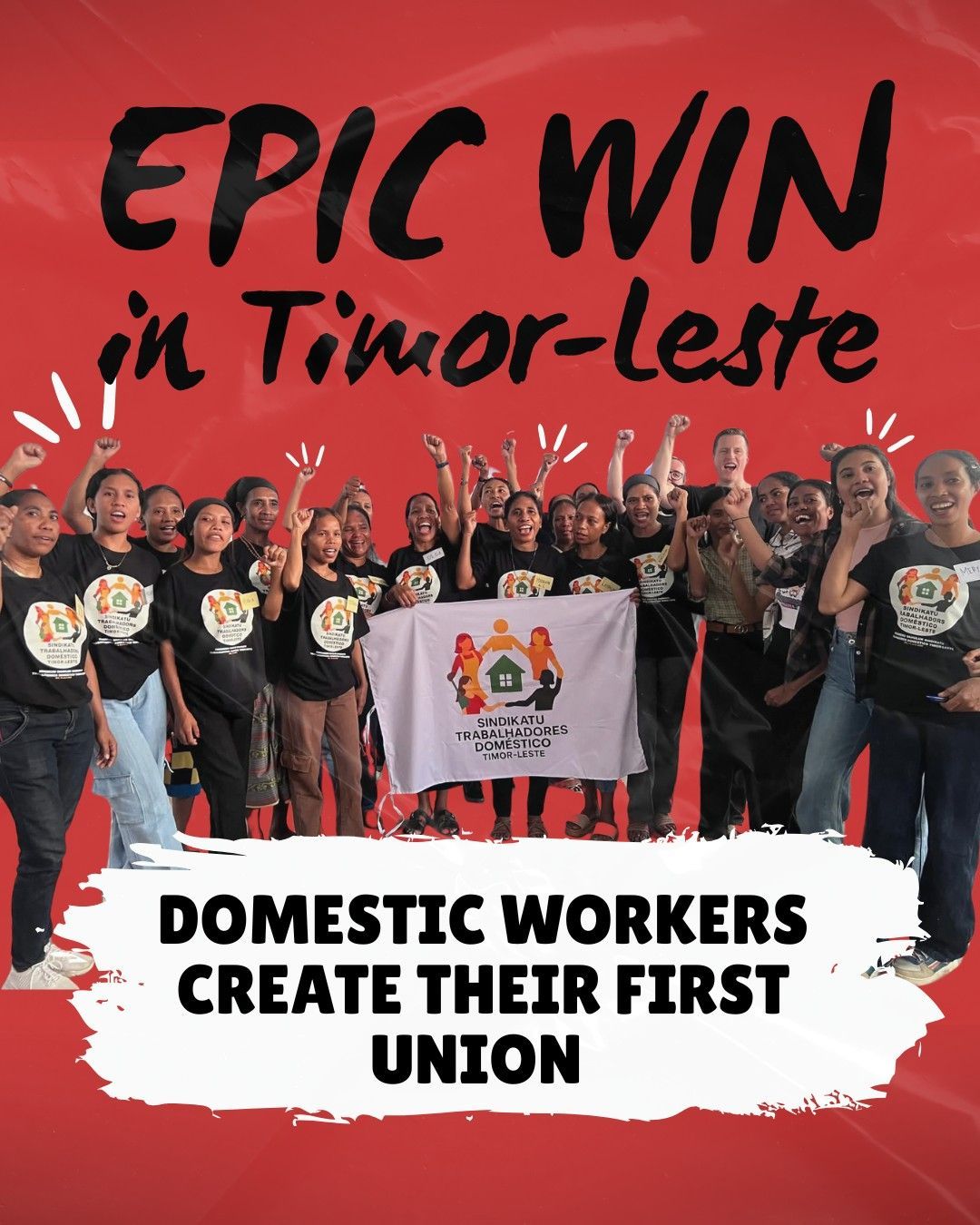 A group of domestic workers in Timor-Leste standing together, many raising their fists in celebratio