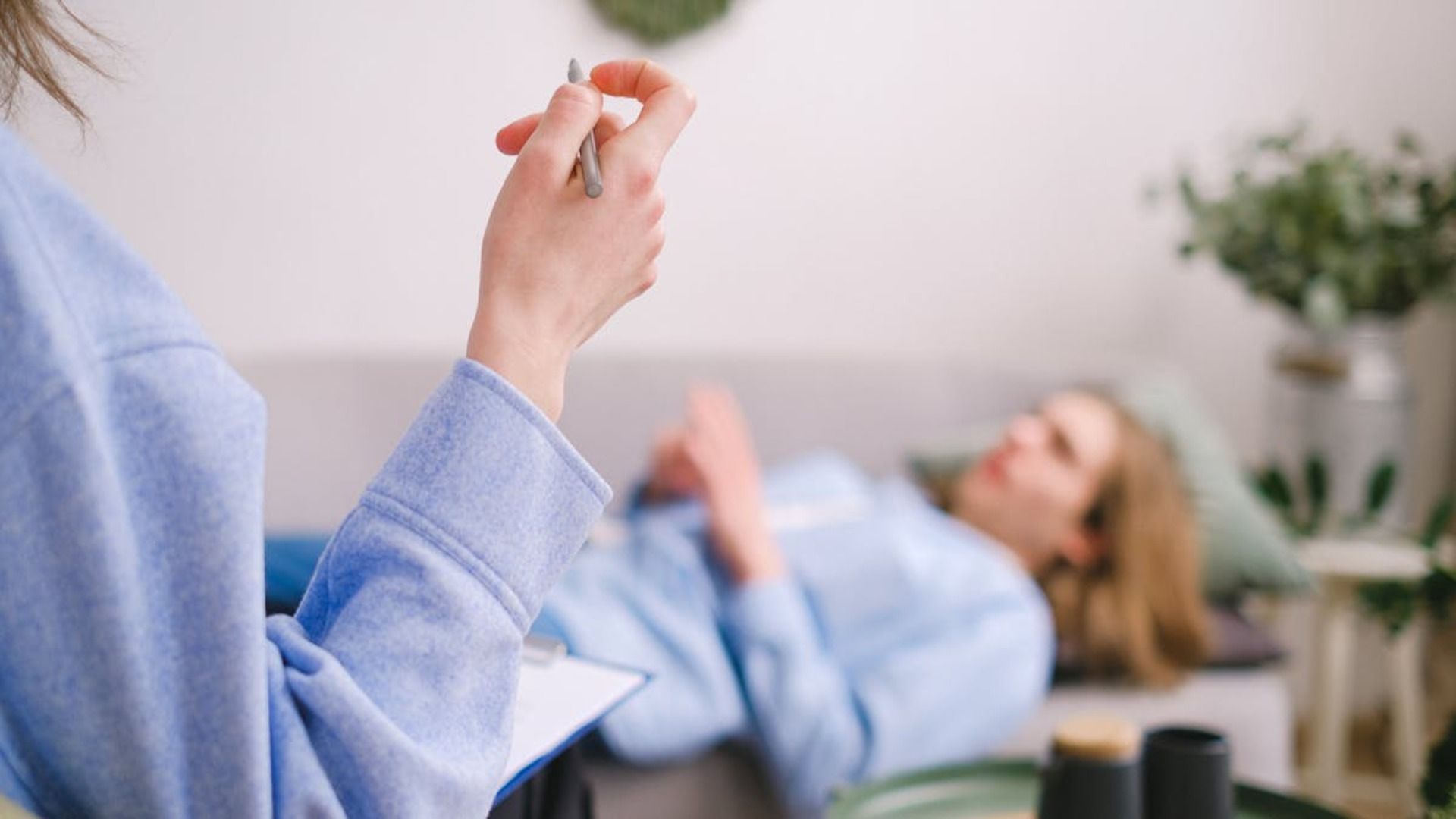En primer plano, una terapeuta sostiene un bolígrafo y un cuaderno.