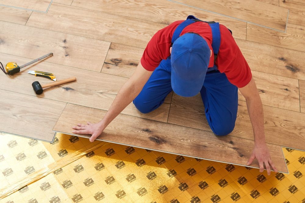 A man is kneeling down on a wooden floor.