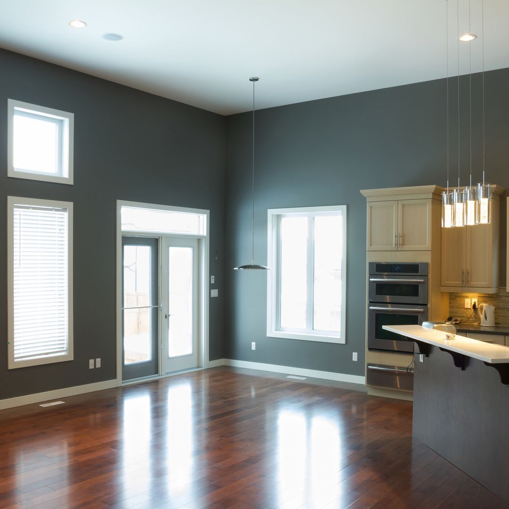 An empty kitchen with gray walls and hardwood floors.