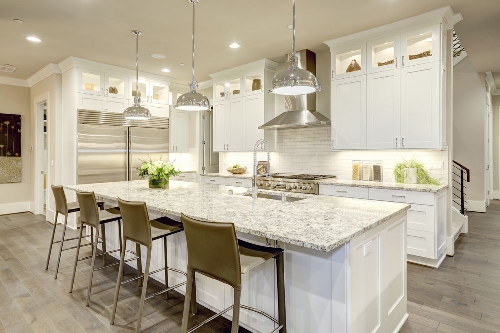 A kitchen with white cabinets , granite counter tops and wooden flooring.