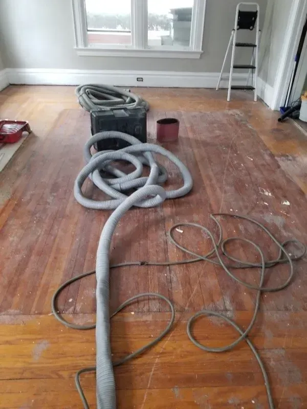A vacuum cleaner is sitting on a wooden floor in a room.