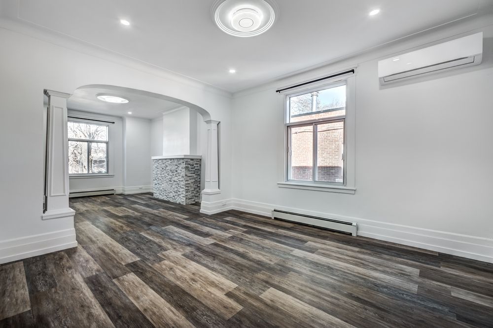 An empty living room with hardwood floors and white walls.