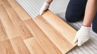 A person is installing a wooden floor in a room.